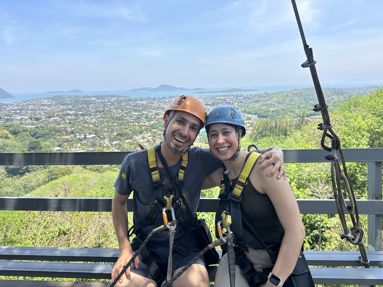 Morty and a companion wearing climbing harnesses above a coastal landscape